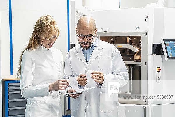 Zwei Techniker in Laborkitteln besprechen den Plan