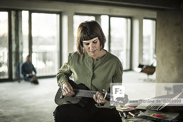 Businesswoman playing the ukulele in office