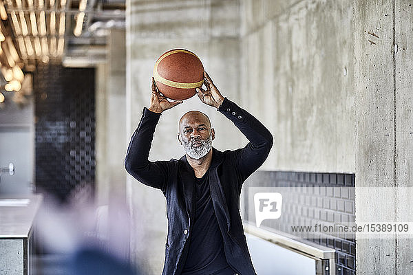 Reifer Geschäftsmann spielt Basketball im modernen Büro