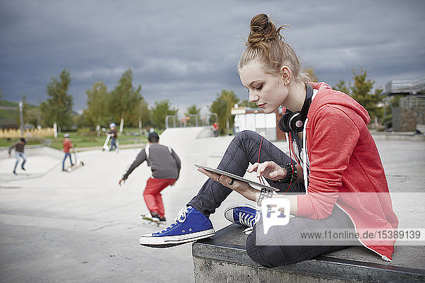 Teenager-Mädchen benutzt Tablette in einem Skatepark