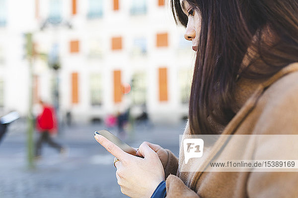 Spanien  Madrid  Nahaufnahme einer jungen Frau  die ihr Smartphone in der Stadt benutzt