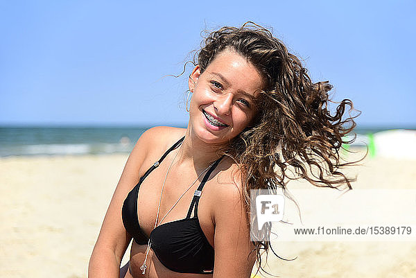 Porträt einer glücklichen Teenagerin mit Zahnspange am Strand