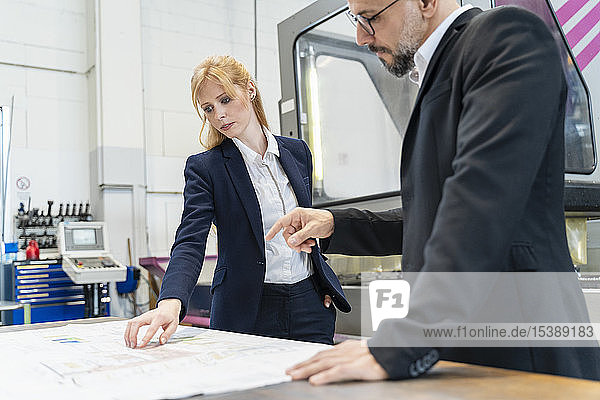 Geschäftsmann und Geschäftsfrau betrachten Plan auf dem Tisch in der Fabrik