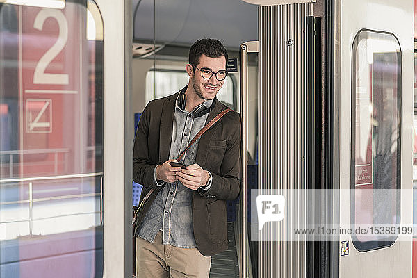 Smiling young man with cell phone in commuter train