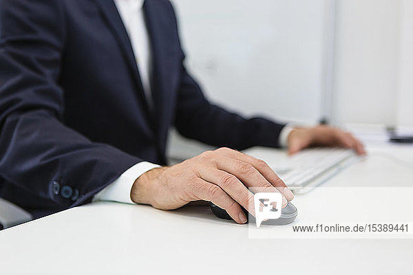Close-up of businessman using computer at desk in office