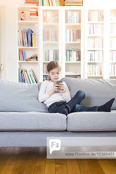 Girl sitting on couch at home holding cell phone