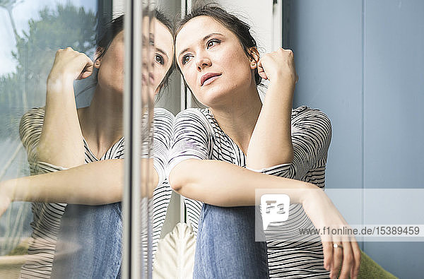Serious woman looking out of window at home