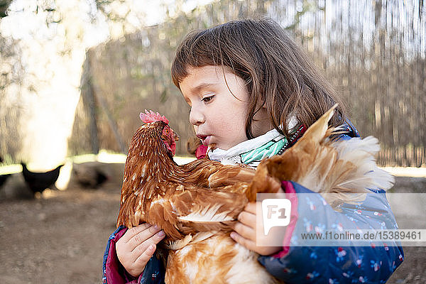 Kleinkind spricht mit Huhn auf dem Arm