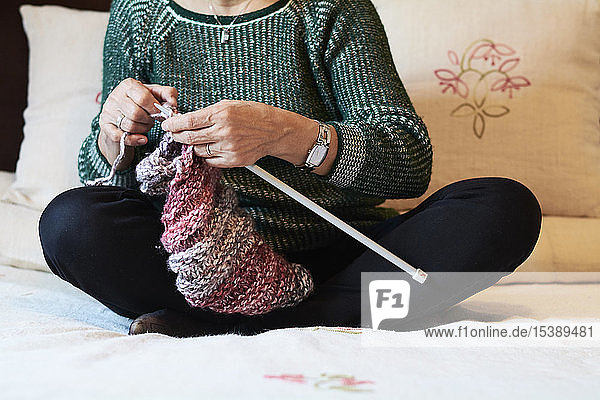 Close-up of woman embroidering sitting on bed at home