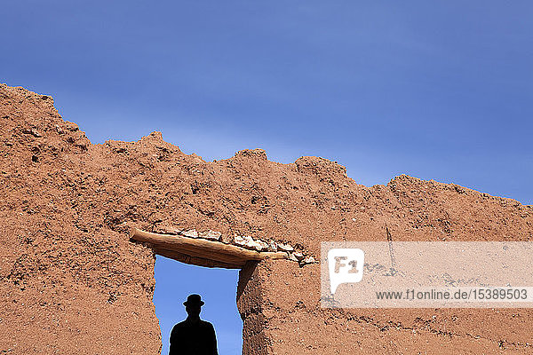 Morocco  Ait-Ben-Haddou  silhouette of man wearing a bowler hat under loam wall