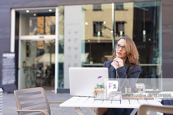 Reife Geschäftsfrau mit Laptop in einem Café im Freien