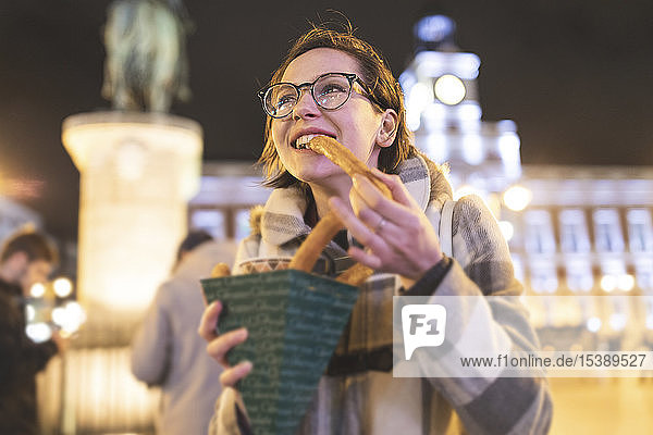 Spanien  Madrid  junge Frau in der Stadt  die abends typische Churros mit Schokolade isst