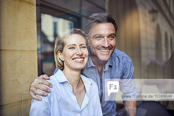 Porträt eines glücklichen Paares hinter einer Fensterscheibe