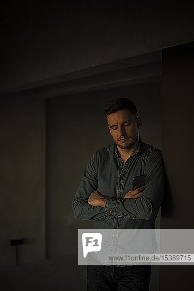 Exhausted businessman leaning on wall with arms crossed