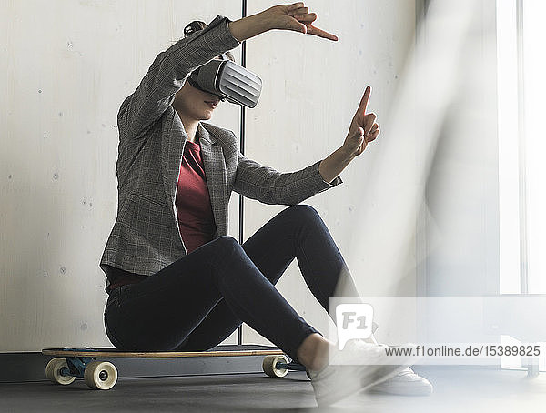 Businesswoman sitting on skateboard in office wearing VR glasses