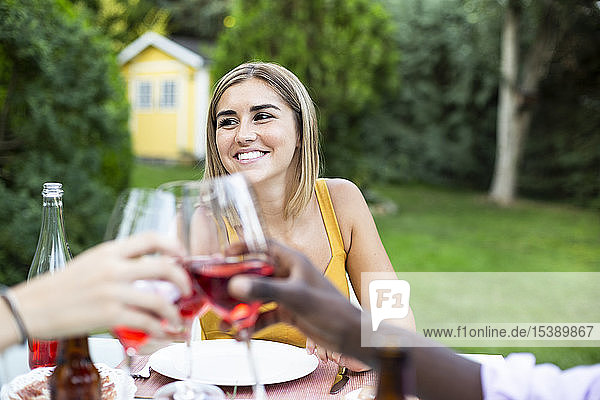 Freunde stoßen mit Wein an ata Sommerabendessen im Garten