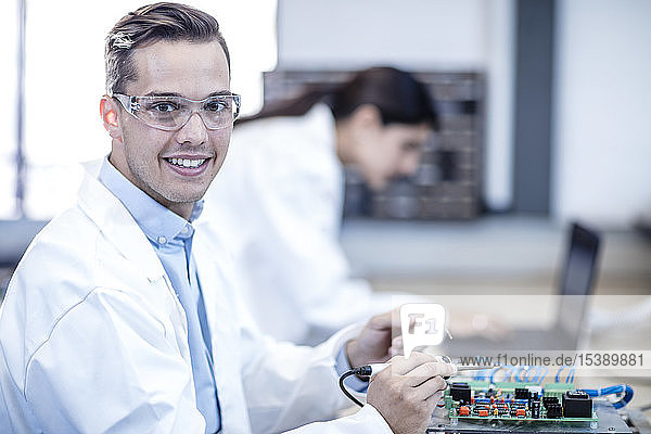 Porträt eines lächelnden Technikers  der an der Hauptplatine arbeitet