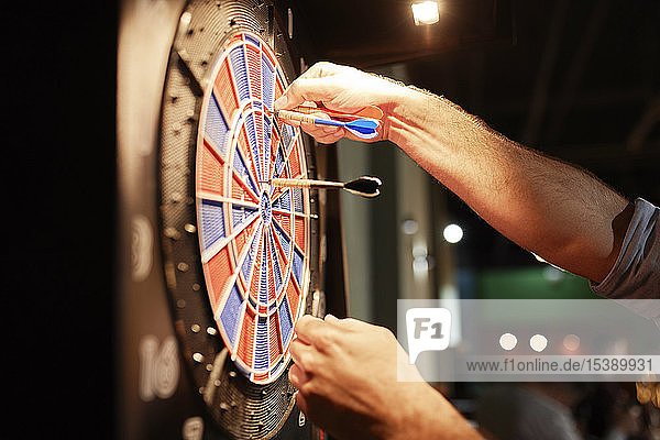 Close-up of man taking out darts from electronic dartboard