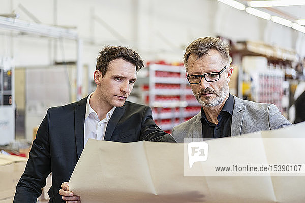 Zwei Geschäftsleute besprechen Plan in einer Fabrik