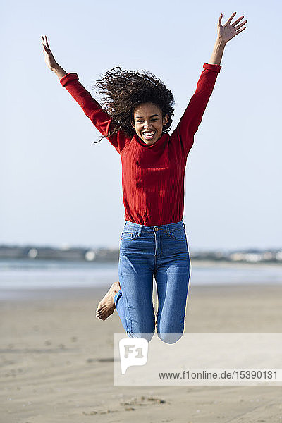 Carefree young woman jumping on the beach