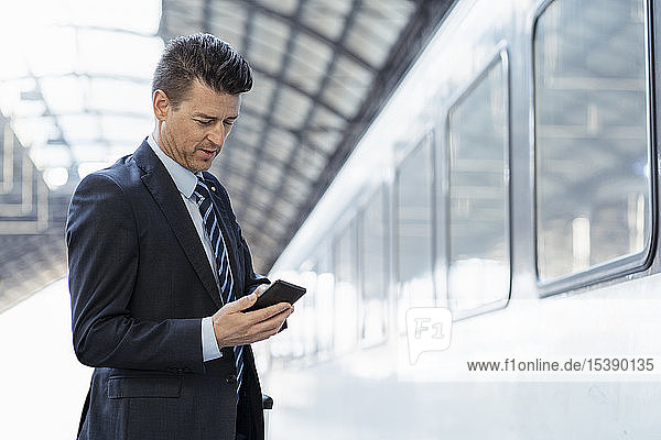 Businessman using cell phone on station platform