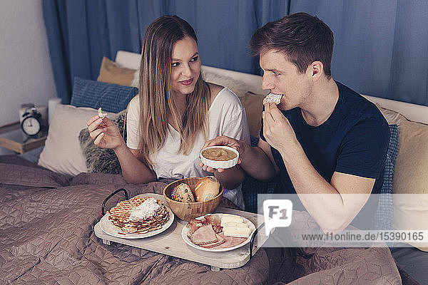 Junges Paar beim Frühstück im Bett