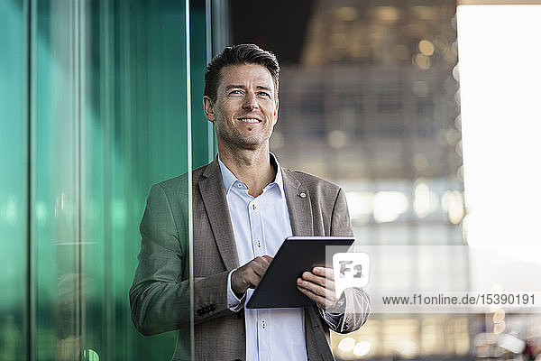 Smiling businessman using tablet outdoors