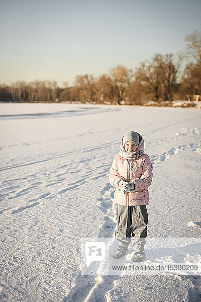 Porträt eines kleinen Mädchens auf einem Schneefeld stehend