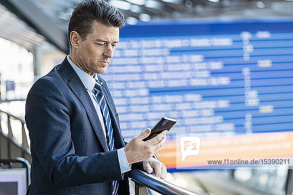 Businessman checking cell phone at the station