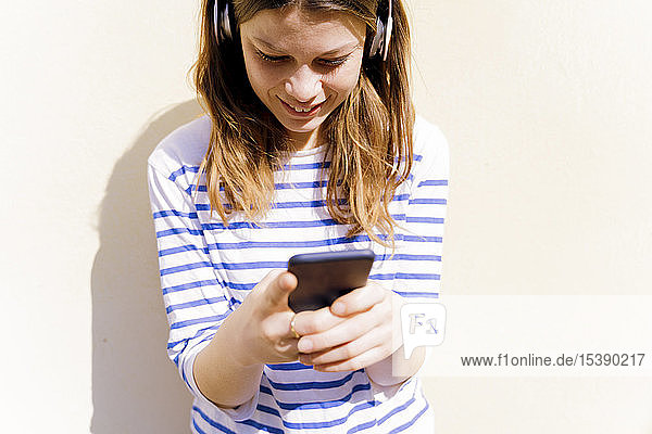 Junge Frau sith Geadphones mit Smartphone
