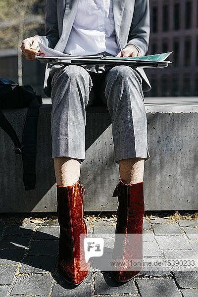 Junge Geschäftsfrau mit roten Schuhen  auf einer Bank in der Stadt sitzend  am Laptop arbeitend  niedrige Sektion