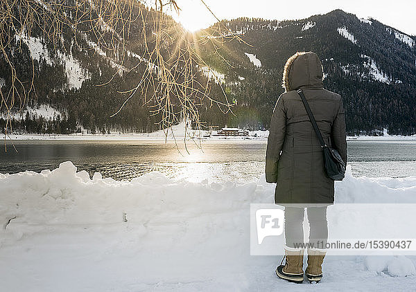 Österreich  Tirol  Achensee  Frau steht im Winter bei Sonnenuntergang am See