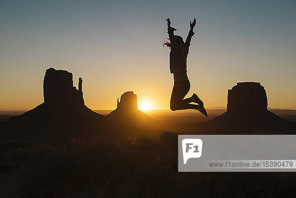 USA  Utah  Monument Valley  Silhouette einer glücklichen Frau  die bei Sonnenaufgang in die Luft springt