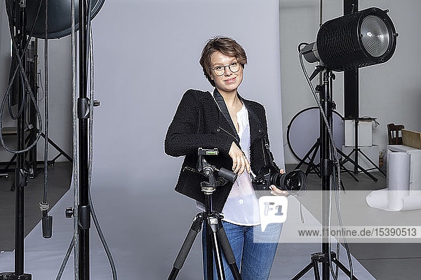 Portrait of smiling young photographer with equipment at photographic studio