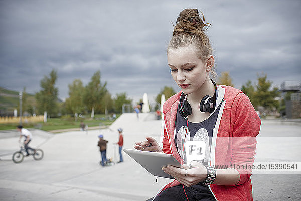 Teenage girl using a tablet at a skatepark