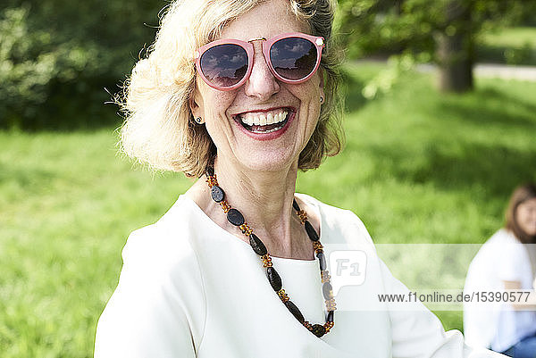 Porträt einer glücklichen älteren Frau mit Sonnenbrille im Park