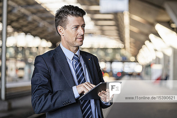 Businessman using tablet at train station
