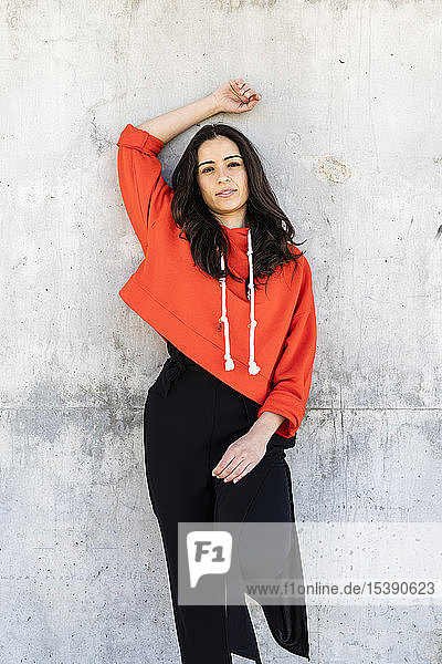 Young contemporary dancer wearing red hoodie shirt in front of a wall