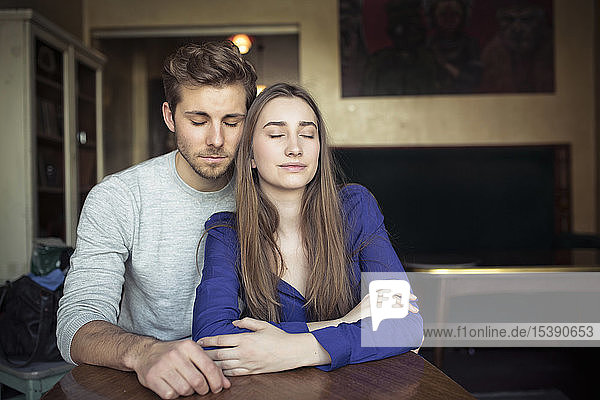 Portrait of young couple in a cafe with closed eyes