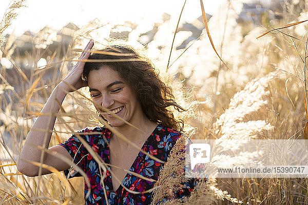 Portrait of a young woman standing in meadow  laughing