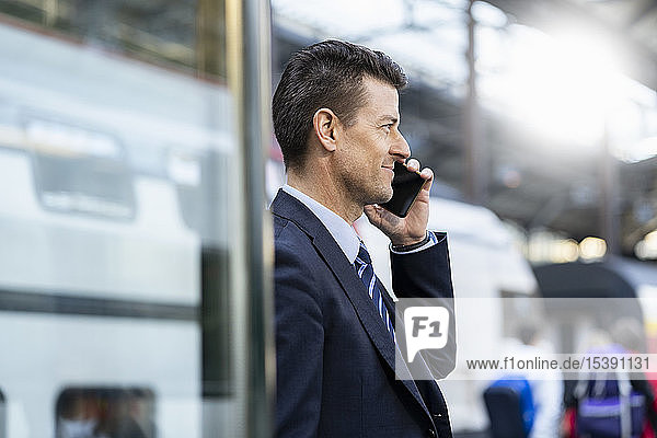 Businessman on cell phone at train station