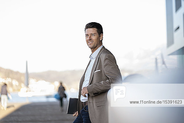 Lächelnder Geschäftsmann mit im Freien stehender Tablette