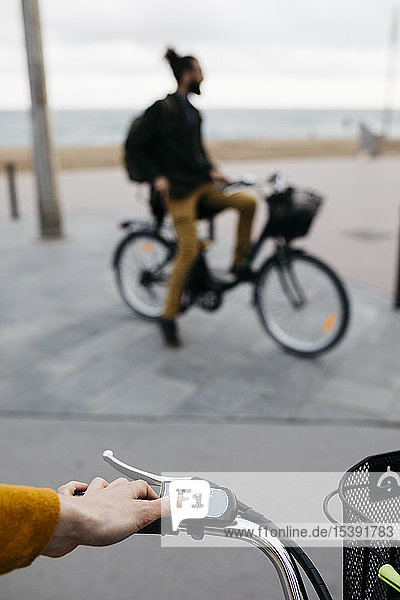Nahaufnahme einer Frau auf einem E-Bike  die den Elektromotor mit dem Mann im Hintergrund verbindet