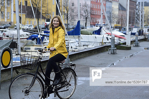 Dänemark  Kopenhagen  glückliche Frau fährt bei Regenwetter Fahrrad im Stadthafen