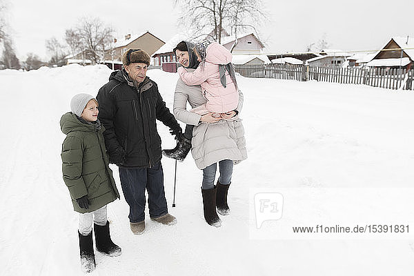 Grossvater zusammen mit Tochter und Enkelkindern im Schnee