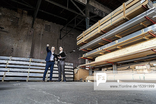 Two businessmen with folder talking in an old storehouse