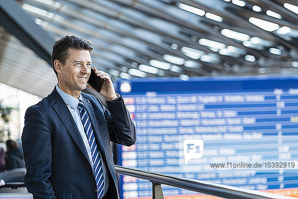Smiling businessman on cell phone at the station