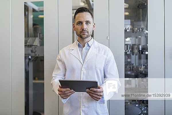 Portrait of man with tablet wearing lab coat in modern factory
