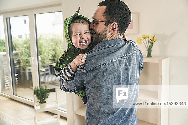 Father playing with happy son in a costume at home