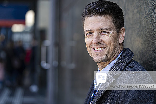 Portrait of smiling businessman at a wall
